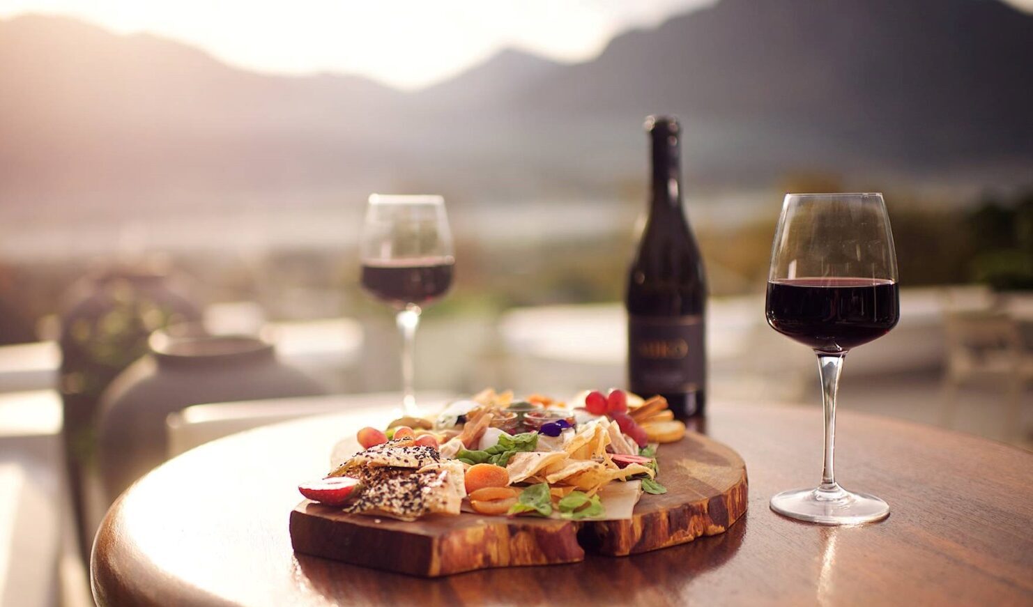 Fles rode wijn en een borrelplankje met de Franschhoek bergen op de achtergrond
