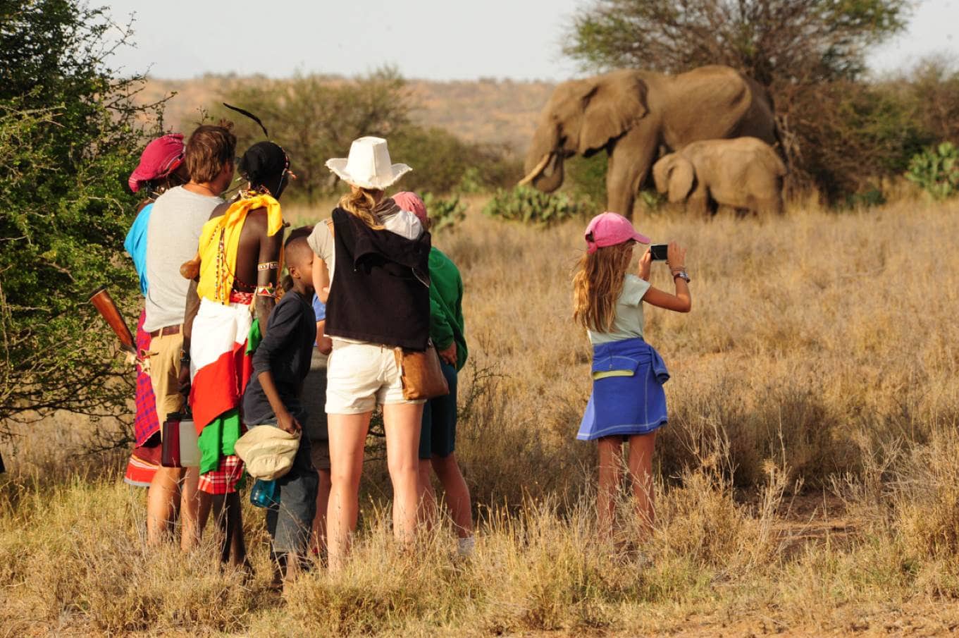 Actieve familie met lokale gidsen van Tumaren Camp spotten olifanten tijdens wandelsafari in Loisaba reservaat